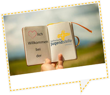 Hand, die ein Notizbuch in den Himmel hält. Im Notibuch steht Herzlich Willkommen bei der Katholischen Jugendstelle Straubing