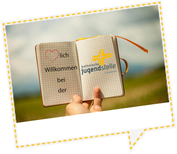 Hand, die ein Notizbuch in den Himmel hält. Im Notibuch steht Herzlich Willkommen bei der Katholischen Jugendstelle Straubing